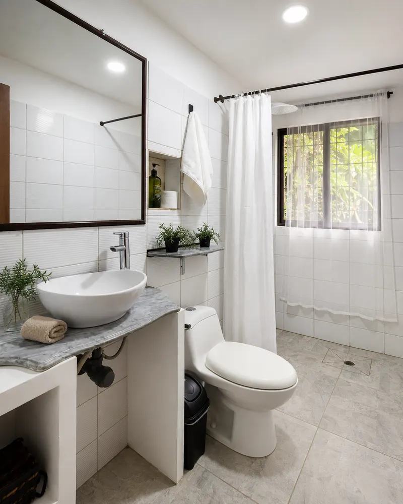 Baño con lavamanos, ducha con cortina y ventana a la vegetación