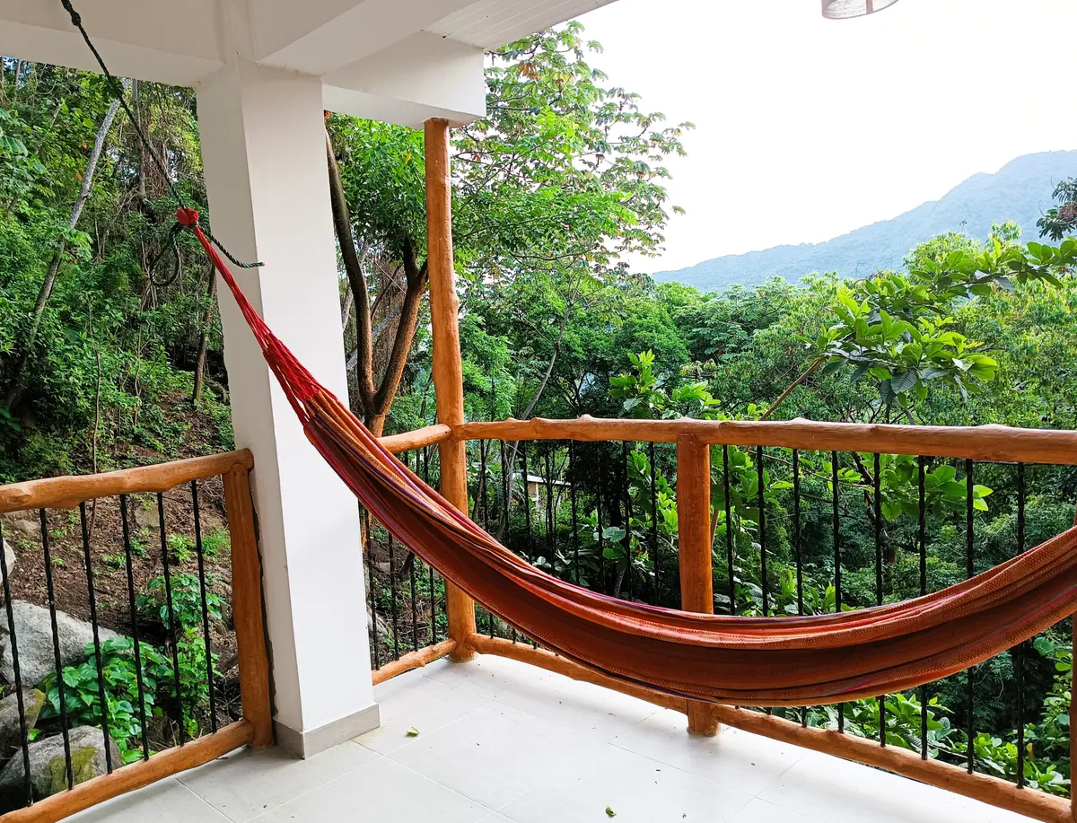 Terraza privada del apartamento con hamaca, rodeada de bosque tropical y con vista a las montañas de la Sierra Nevada
